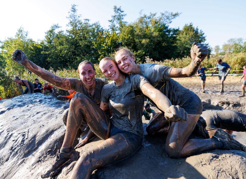 vriendinnen die lachend in de modder zitten tijdens de 4 km run van strong viking