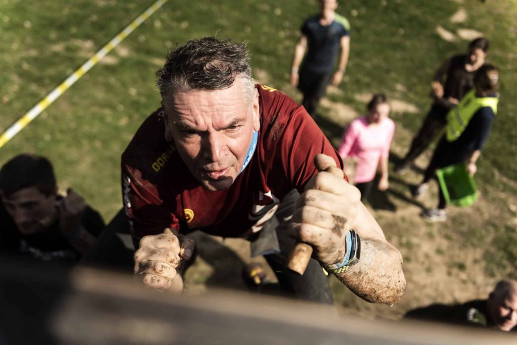 Man climbing up during Strong Viking (photo for preventing muscle soreness after an obstacle run, reducing muscle soreness and muscle pain)