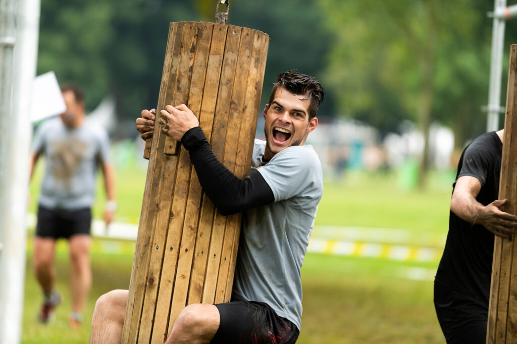 Man hanging from a wooden obstacle. Photo for obstacle run tips for beginners, Strong Viking.