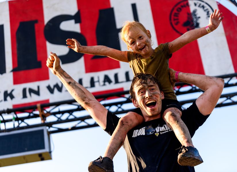 kindje dat op de schouders zit van haar vader tijdens de family run van strong viking