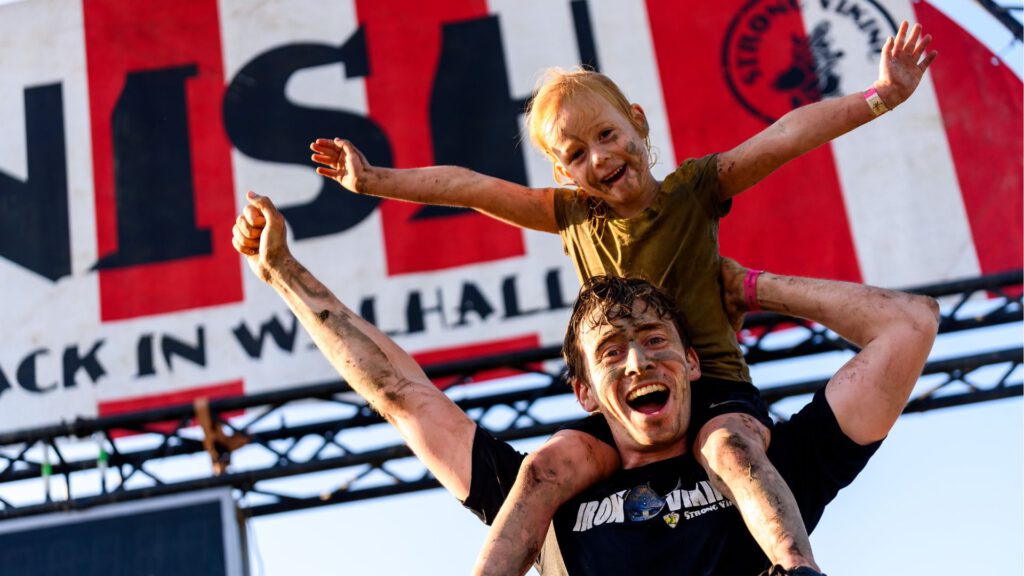 dochter die op de schouders zit van vader bij de finish van de family run
