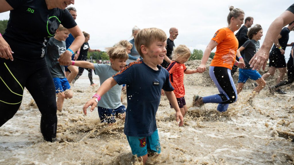 Kinderen die met hun ouders door de modder heen rennen tijdens de strong viking family run