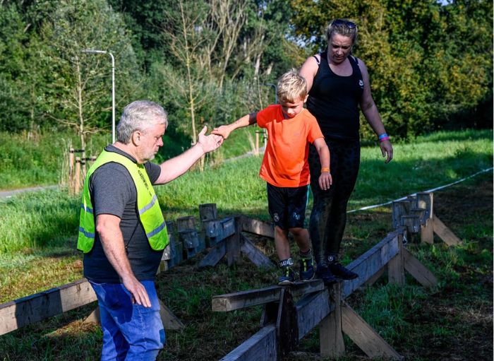 crew member die een jonge deelnemer een obstakel over helpt