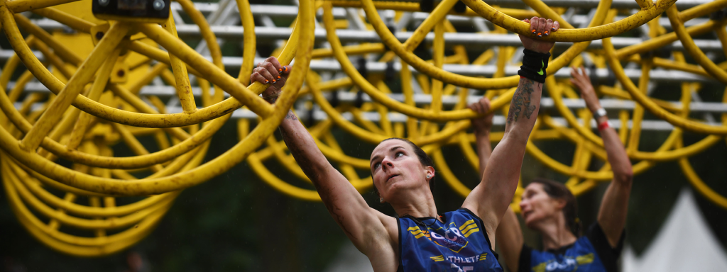 OCR participant testing her grip strength during one of the Strong Viking obstacles (hand grip training, pinch strength training, hand training, grip training, obstacle run grip strength training).
