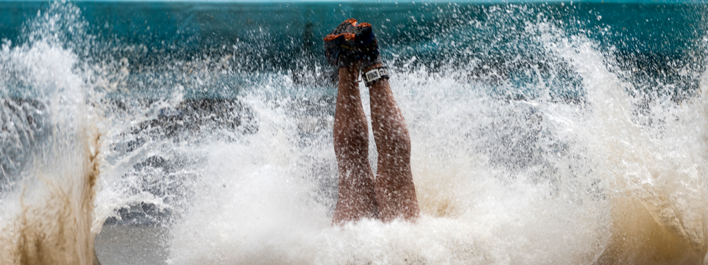 Someone diving into the water during Strong Viking, with only their legs and obstacle run shoes visible (mud run shoes, survival run shoes, mud run running shoes).
