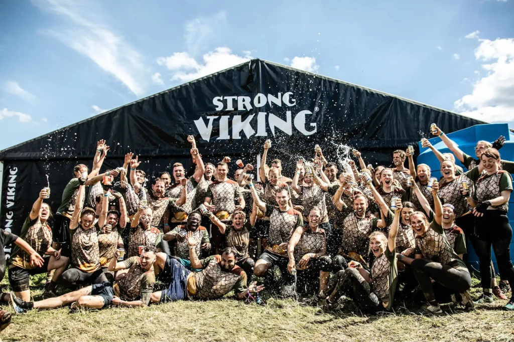 Een groep collega's die juichend en proostend op de foto staan tijdens strong viking